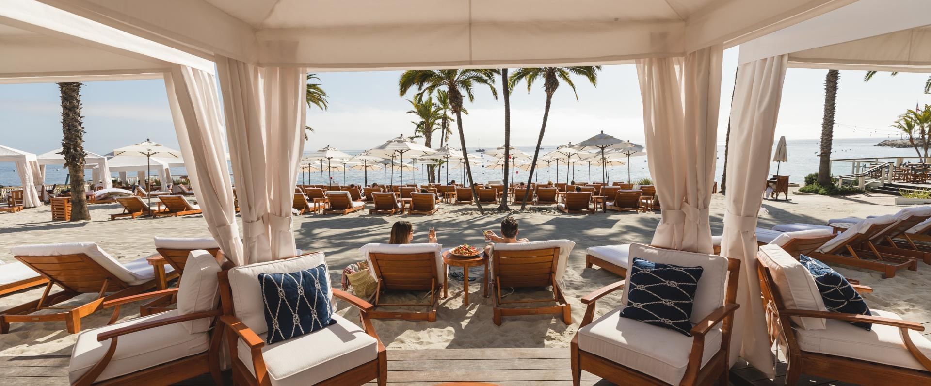 Descanso Beach Club shoreline with umbrellas, beach seating, and turquoise water.